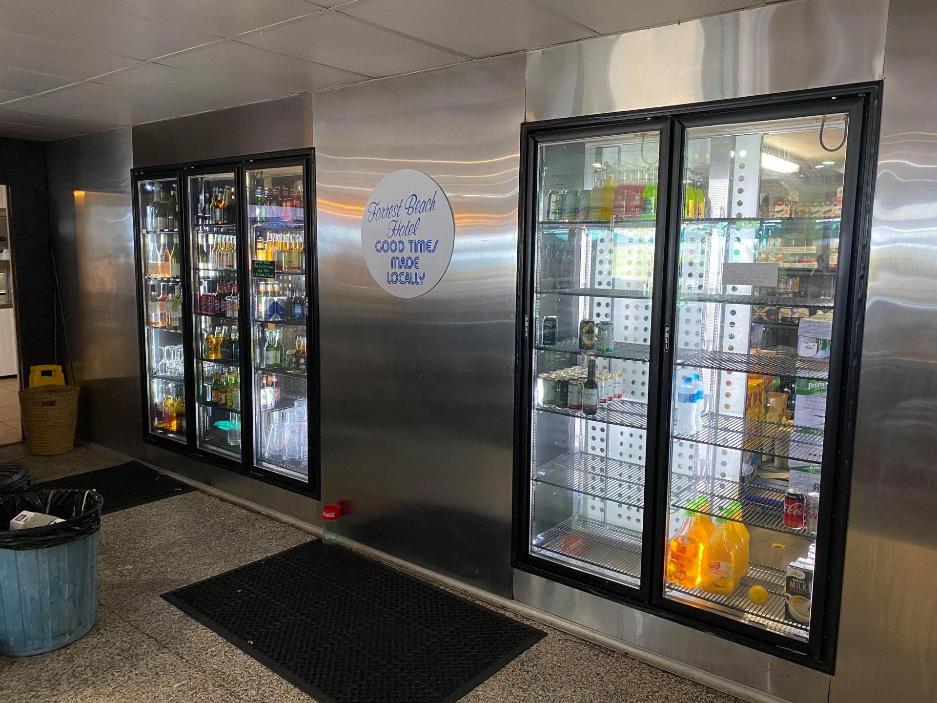 Three refrigerated display cases with beverages and snacks against a stainless steel wall.— Lahtinen Electrical & Refrigeration in Ingham, QLD