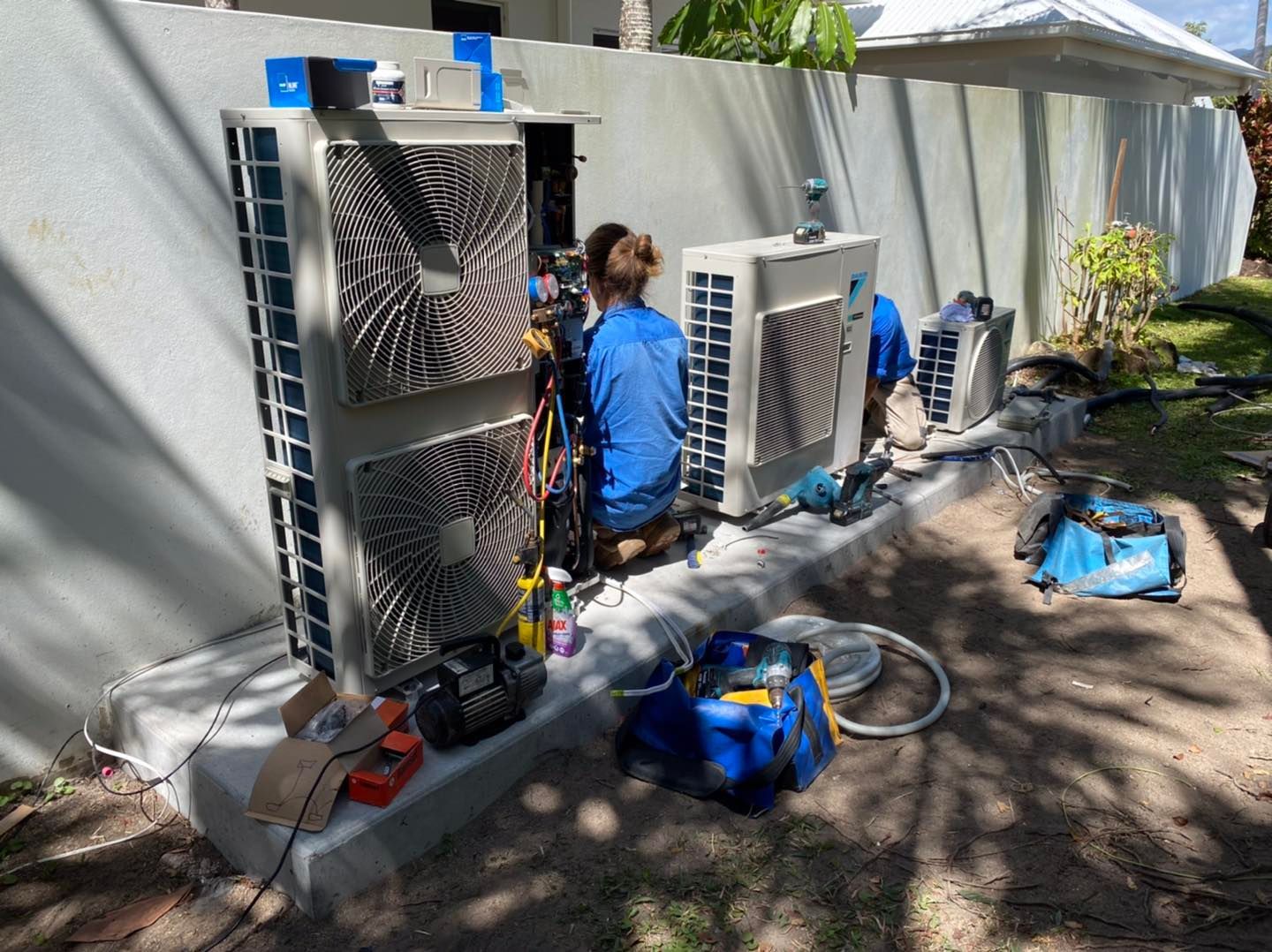 Workers Servicing Air Conditioning Units Outside a Building — Lahtinen Electrical & Refrigeration in Ingham, QLD