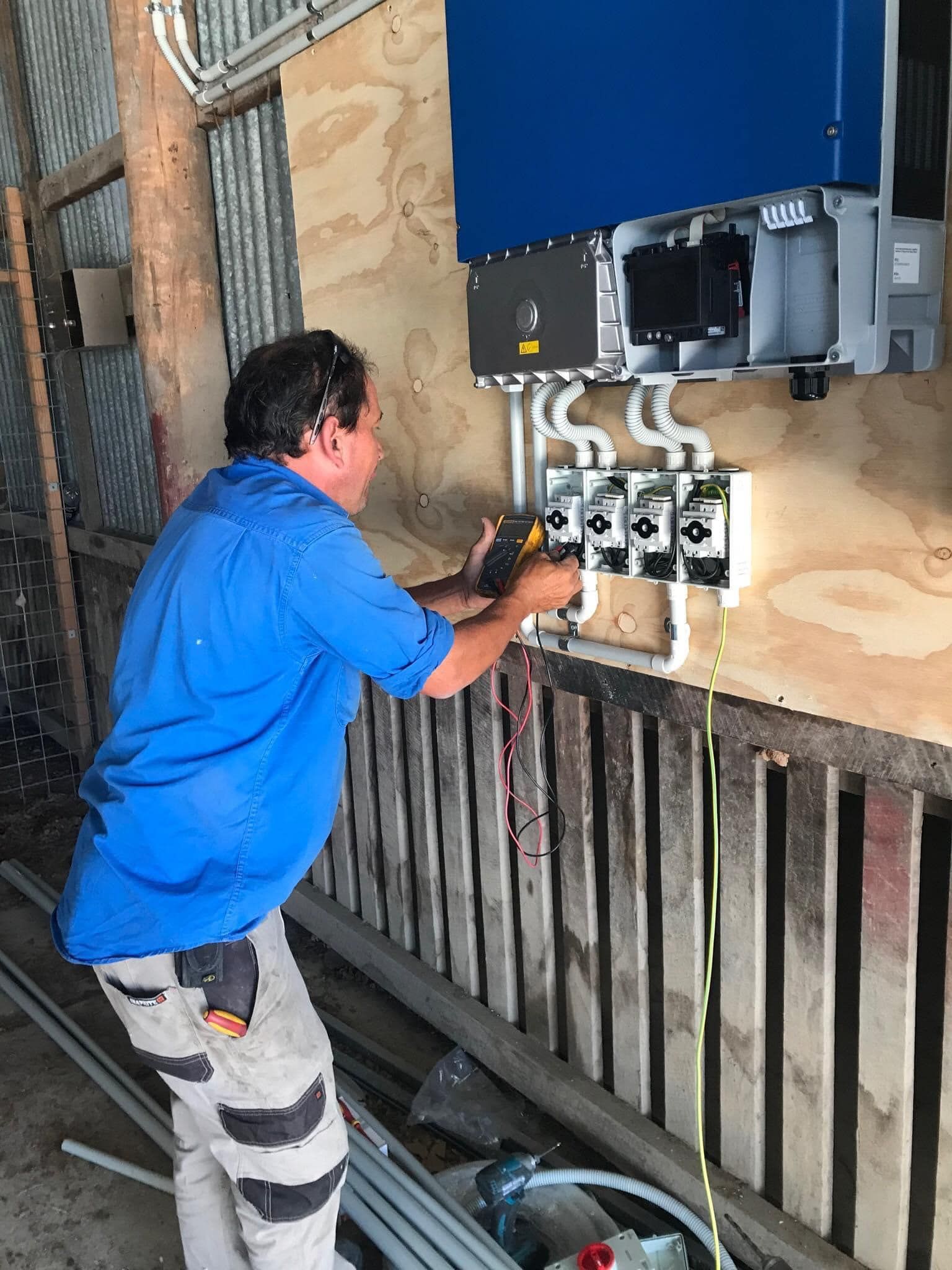 Electrician Working on Electrical Components Mounted on a Wooden Wall — Lahtinen Electrical & Refrigeration in Ingham, QLD