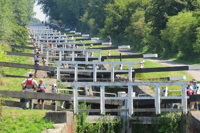 White water sluice with many stepped gates along a green hillside, with a few people standing nearby