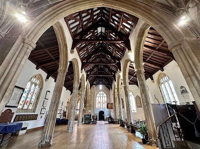 Interior of a historic church with a high wooden vaulted ceiling, stone arches, and stained glass windows