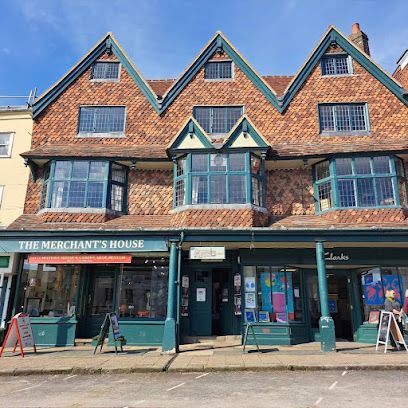 The Merchant’s House storefront with brick gables and a row of shops beneath a blue sky