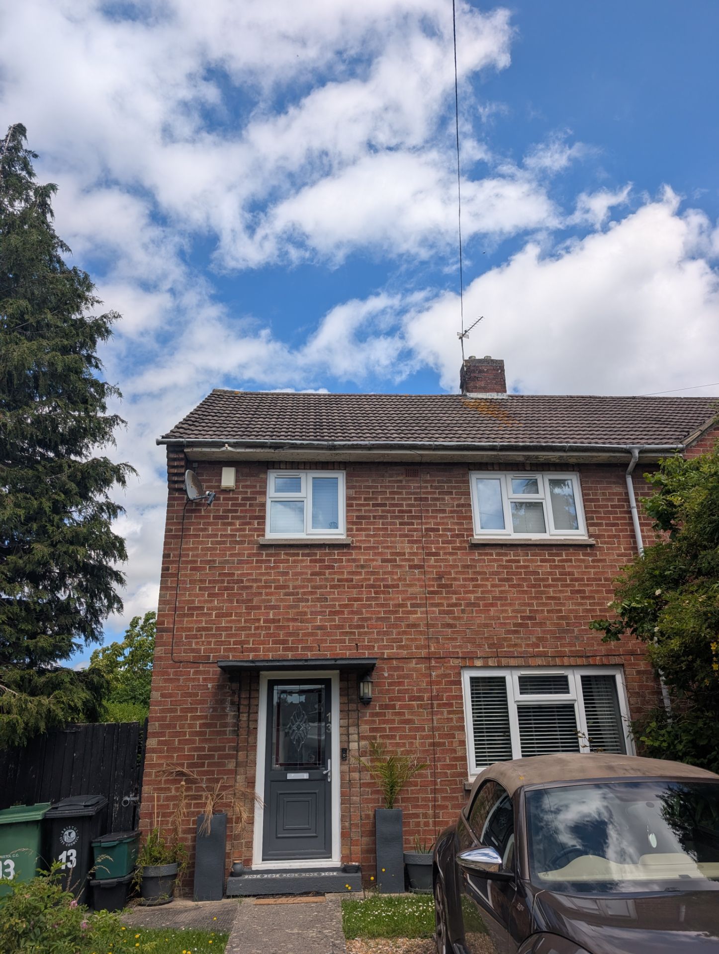 Two-story brick house with a parked car in front under a partly cloudy sky
