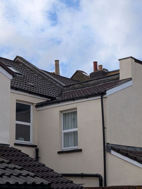 View of white and beige house rooftops and chimneys against a cloudy sky