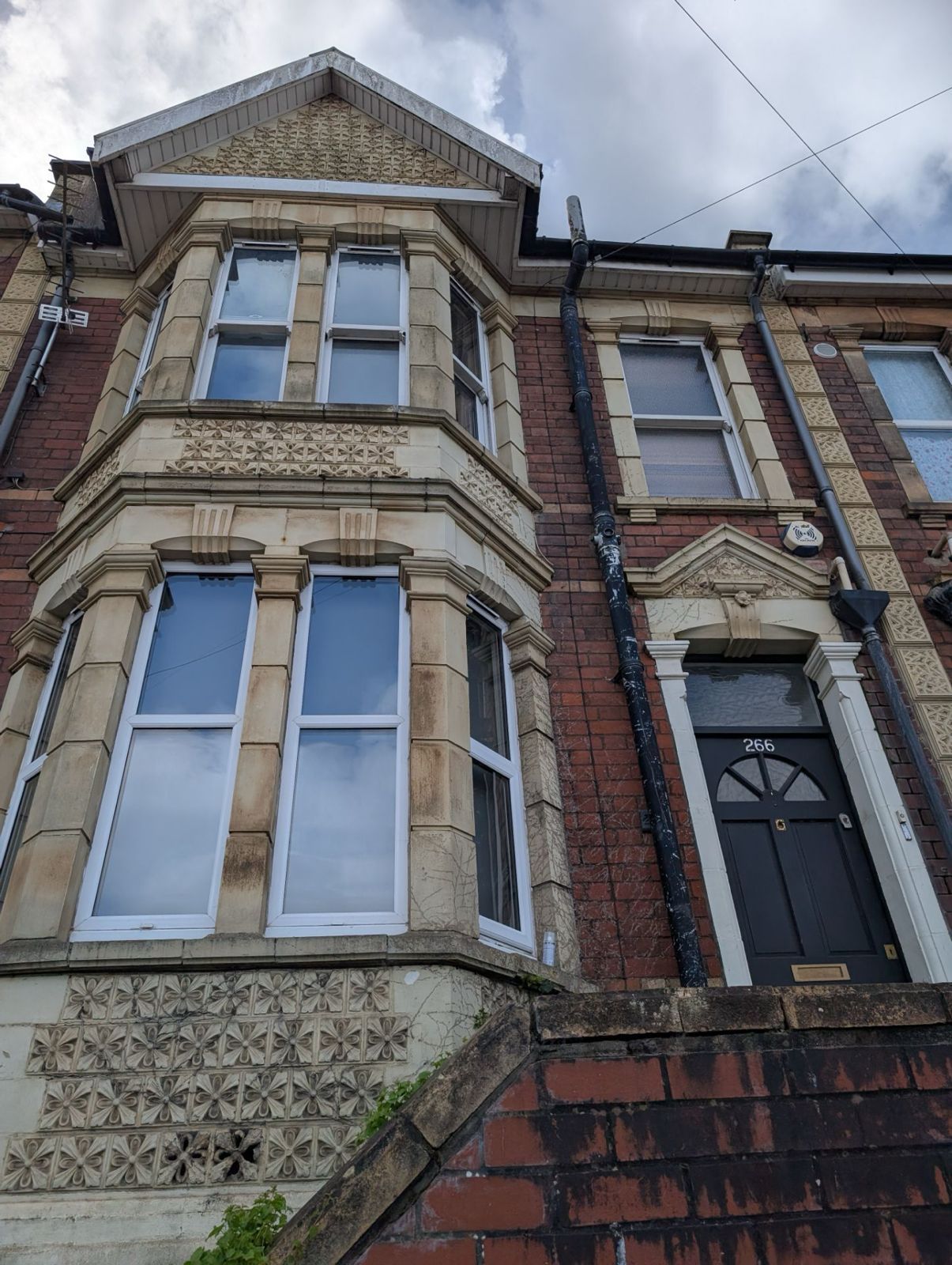 Row of old stone and brick terraced houses with bay windows and a cloudy sky above