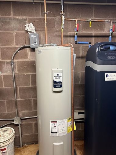 Water heater and blue water softener in a basement utility area against a cinder block wall.