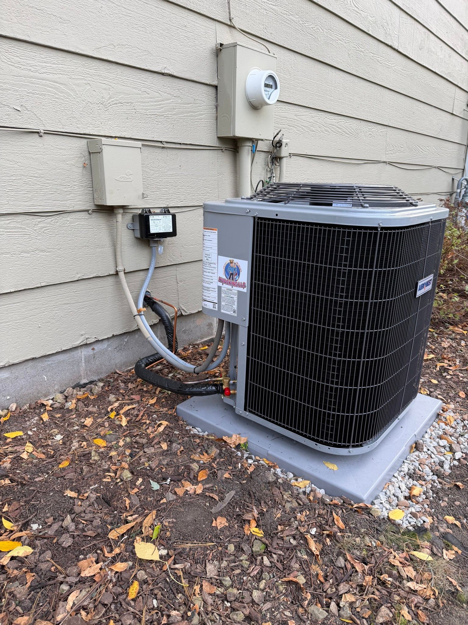 An air conditioning unit on a concrete pad next to a beige house exterior.
