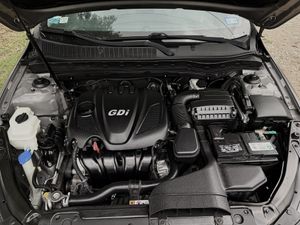 Orange-gloved hand cleaning a car’s gear shift and center console with spray cleaner