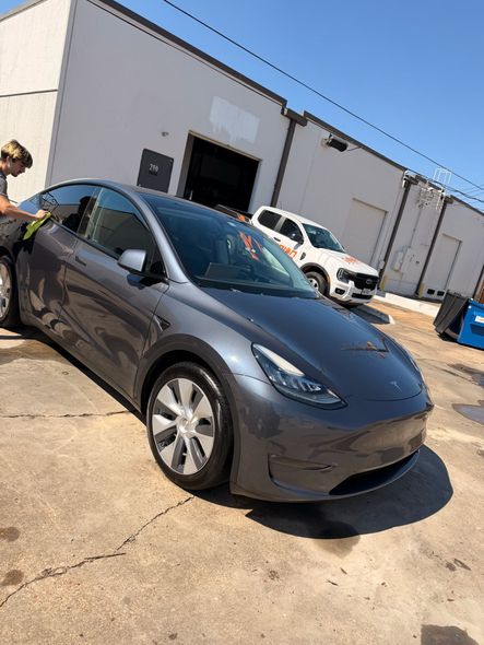Gray Tesla parked outside an industrial building on a sunny day