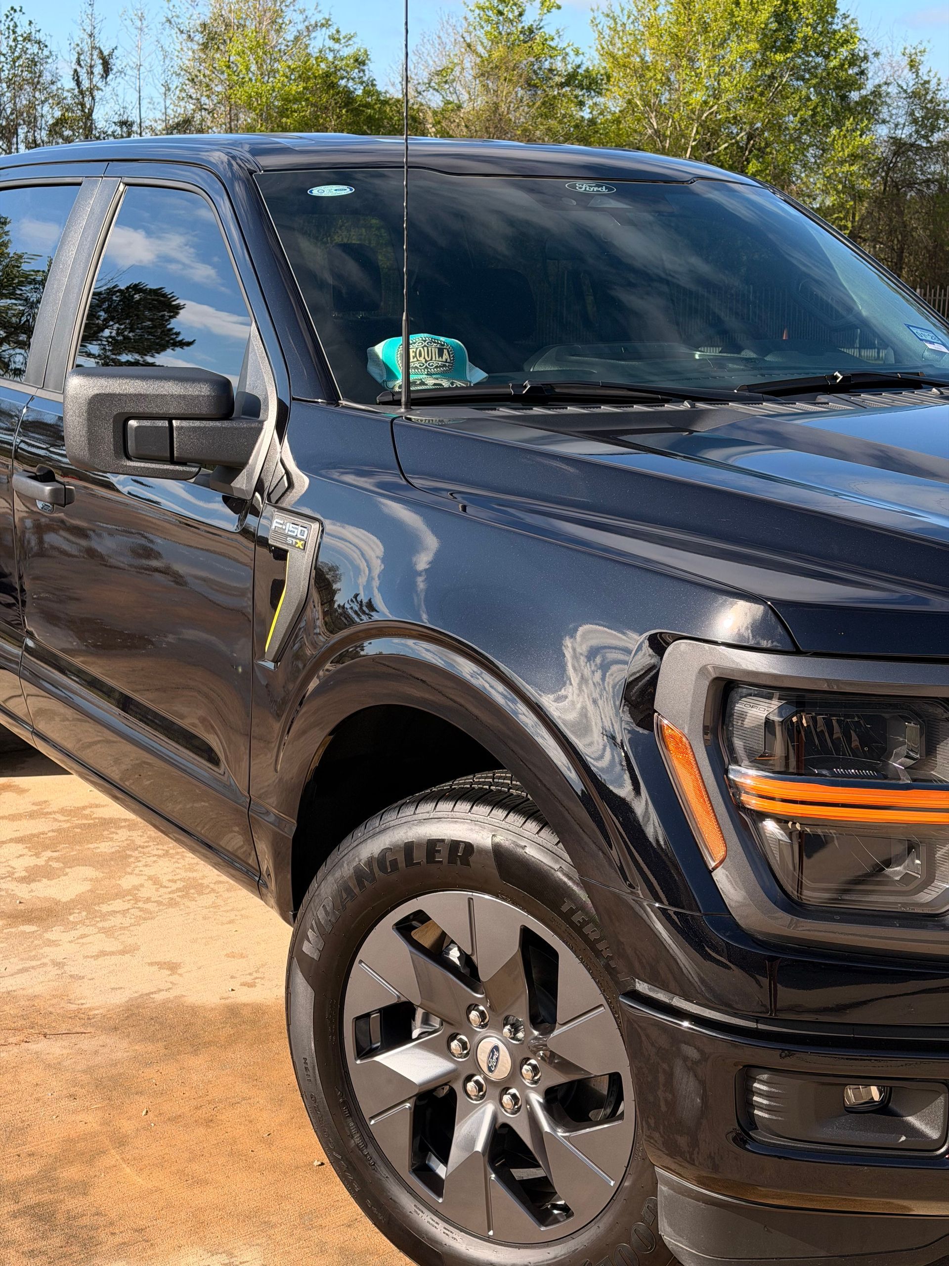 Dark gray SUV parked on a dirt road in a sunny outdoor setting
