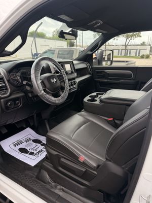 Hands polishing a black car hood with a buffer and blue pad