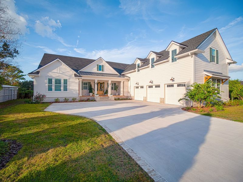 A large white house with a lot of garage doors and a driveway.