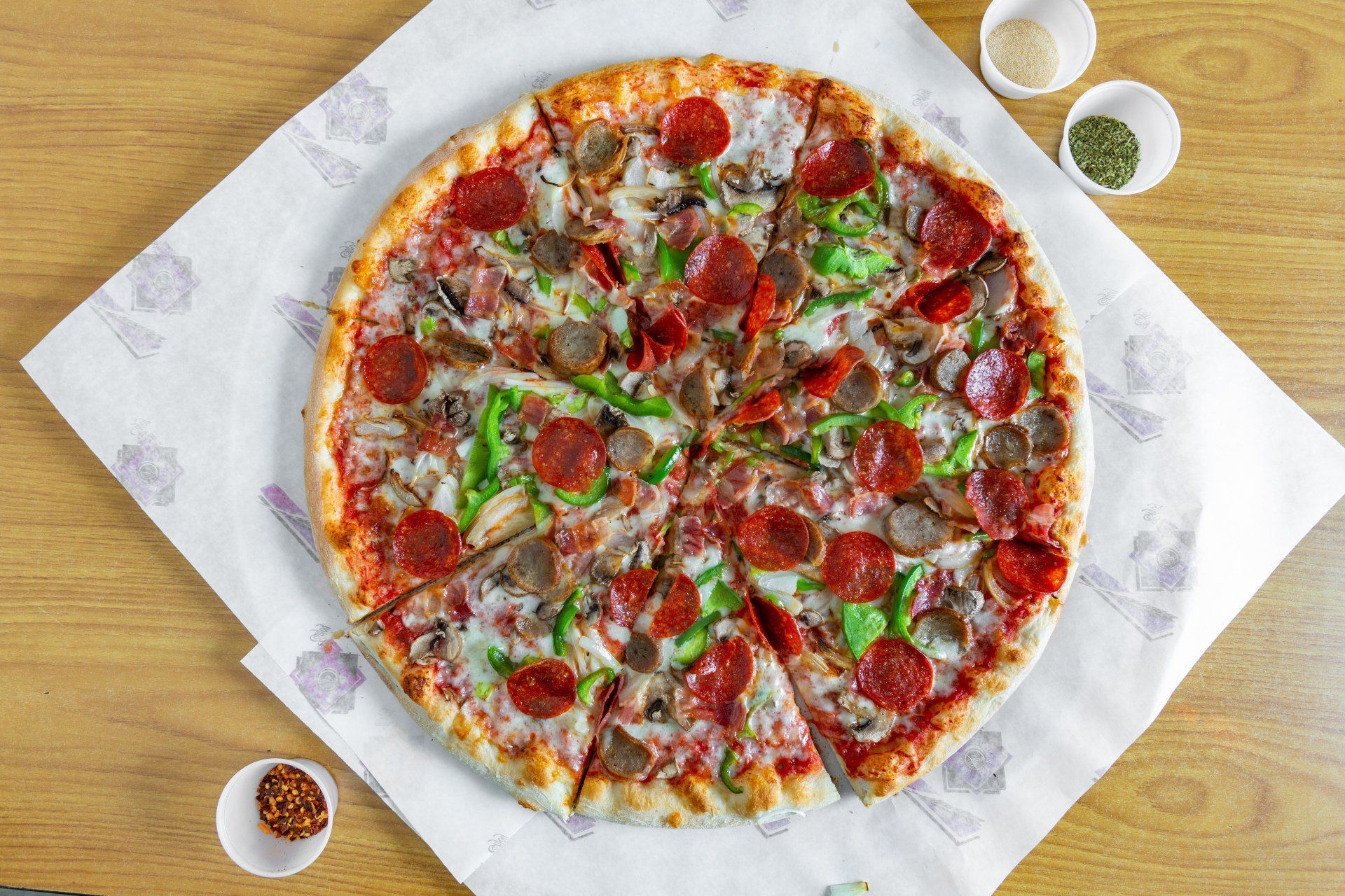 A pizza is sitting on a piece of paper on a wooden table.