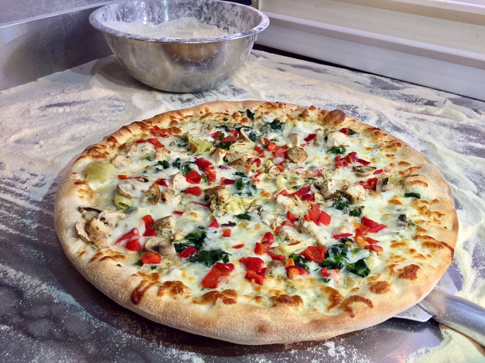 A pizza with a lot of toppings on it is sitting on a table.