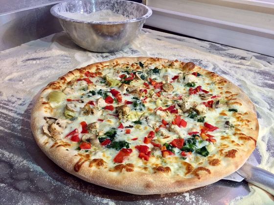 A pizza with a lot of toppings on it is sitting on a table.