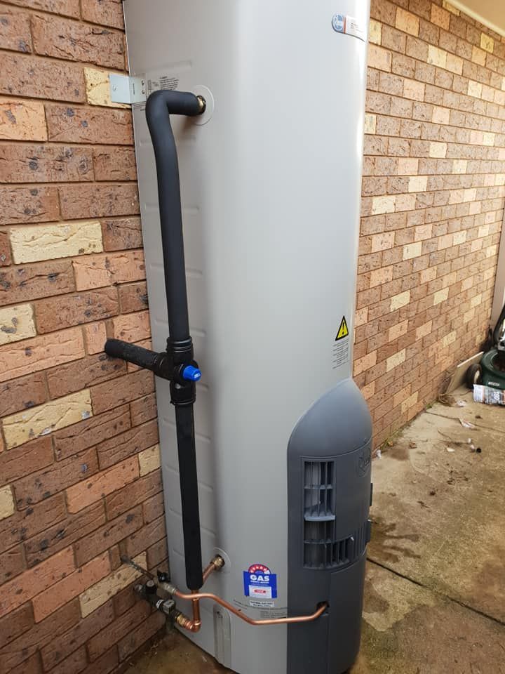 A Water Heater is Sitting on the Side of a Brick Wall — Beaumont Plumbing in Glenfield Park, NSW