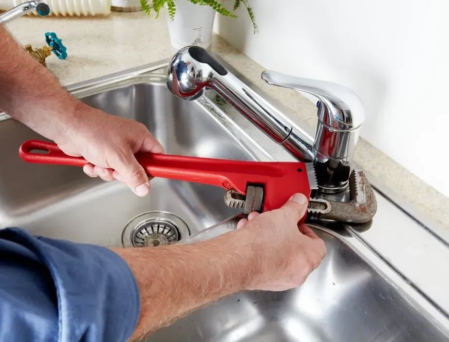 Plumbers Wagga Repairing A Kitchen Sink Tap With A Pipe Wrench For Reliable Plumbing Service And Care