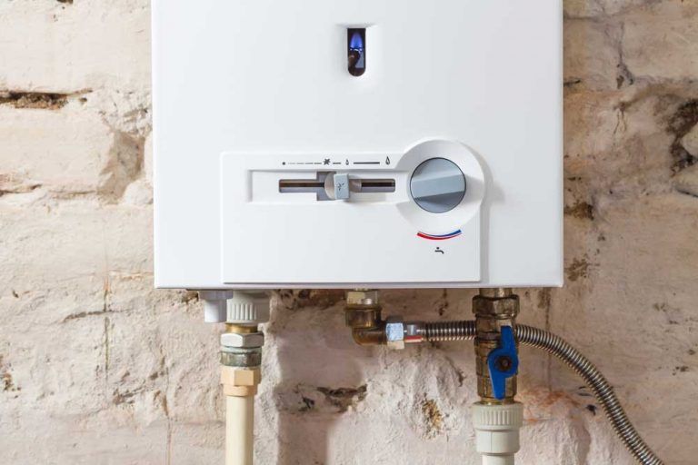 A White Water Heater is Attached to a Brick Wall — Beaumont Plumbing in Glenfield Park, NSW