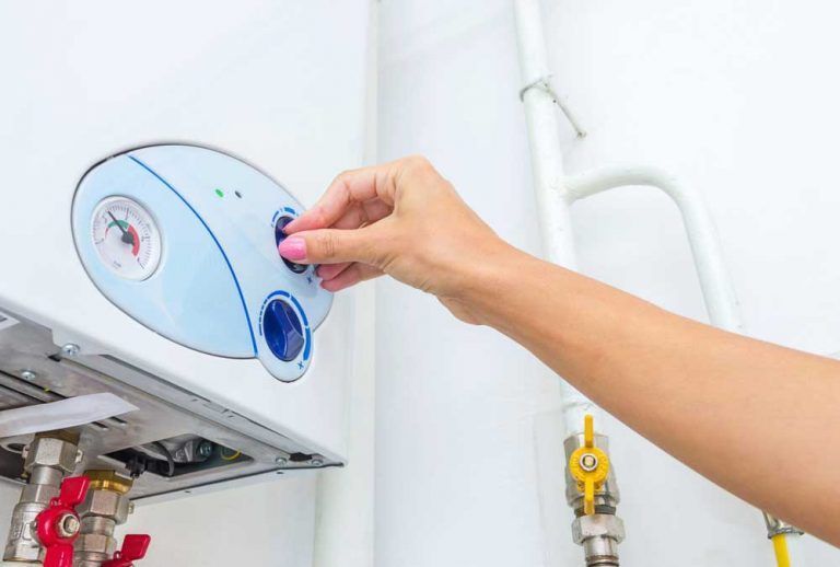 A Person is Pressing a Button on a Boiler — Beaumont Plumbing in Glenfield Park, NSW
