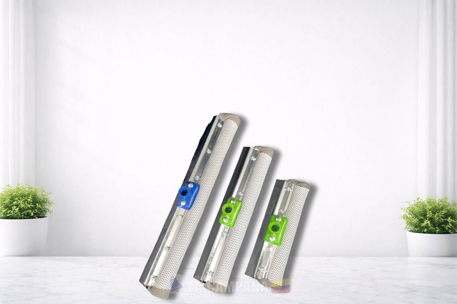 Three shiny metal zippers with colored tags, leaning on a white surface between small green plants.