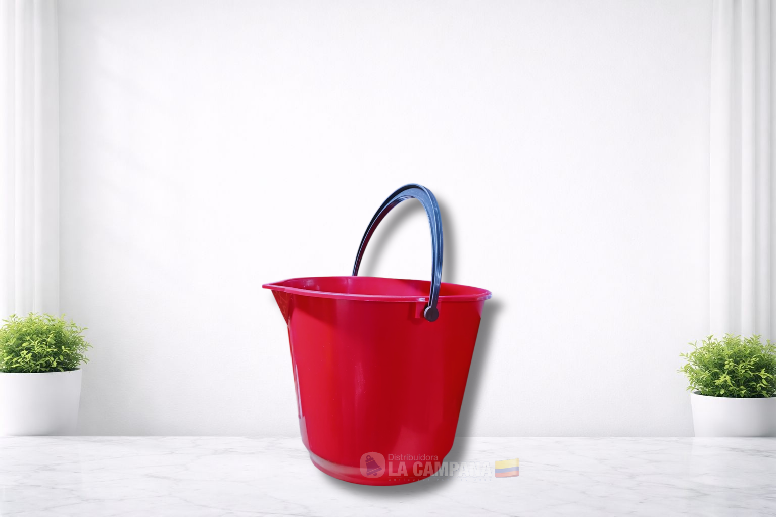 Red bucket with gray handle on a white floor, flanked by two small green plants.