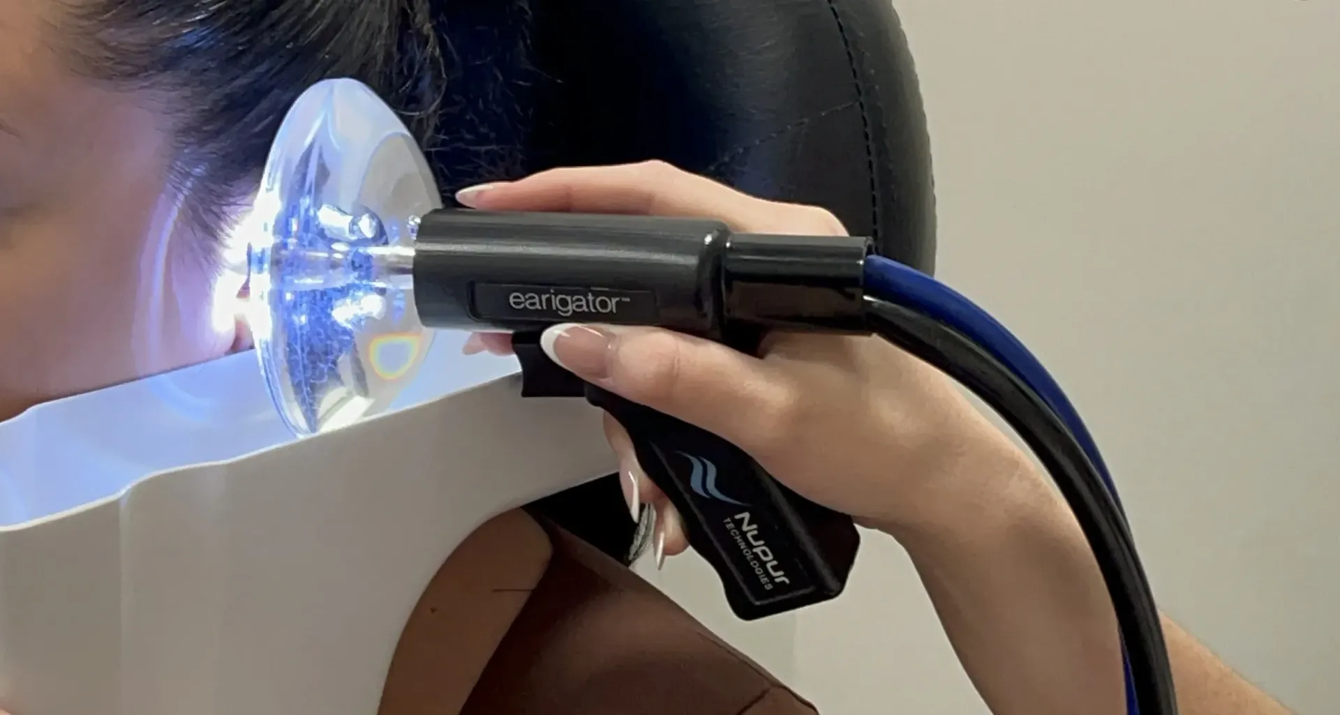 Earigator handpiece positioned at the ear during professional irrigation