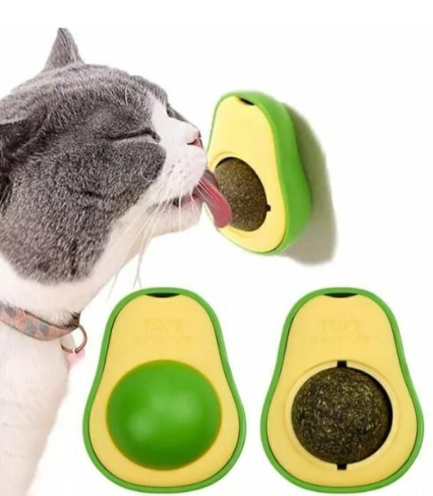 Gato lamiendo un juguete de hierba gatera con forma de aguacate; verde y amarillo, fondo blanco.