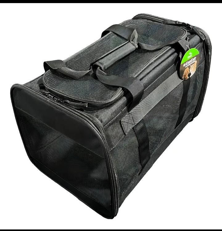 Transportín para mascotas de color negro con laterales de malla, asa y cierre de cremallera.