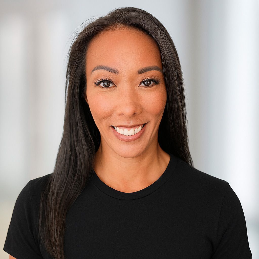 Woman with long dark hair, wearing a black shirt, smiling. Blurred white background.