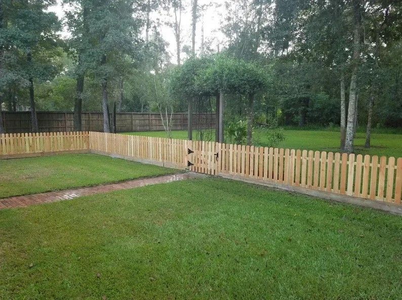 A wooden picket fence surrounds a lush green yard.