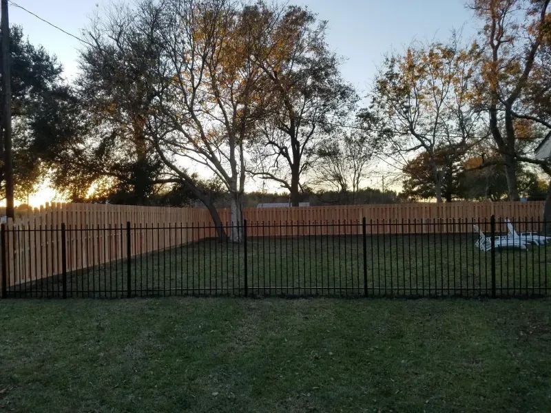 A backyard with a wooden fence and a metal fence