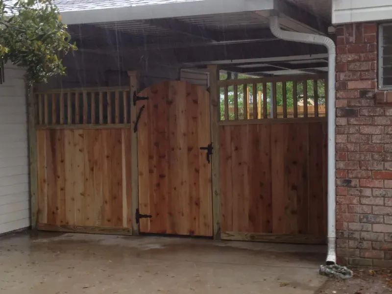 A wooden gate is sitting in front of a brick house.