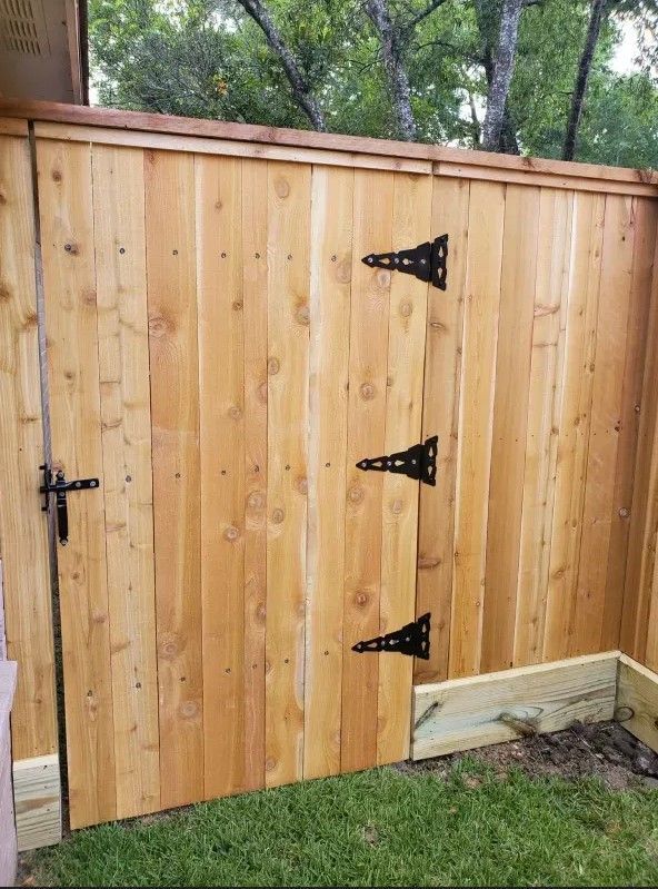 A wooden fence with three black hinges on it