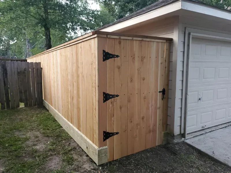 A wooden fence is sitting next to a garage door.