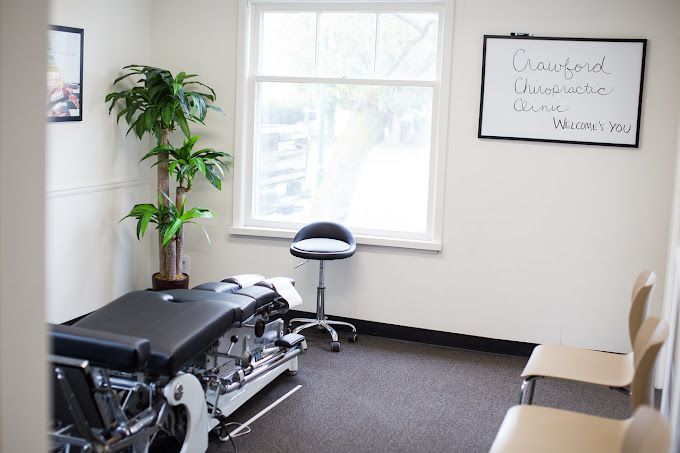 A room with a table and chairs and a whiteboard that says crawford chiropractic