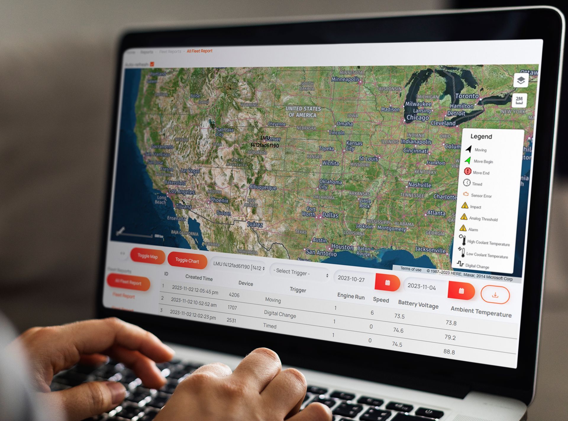 Operator monitoring multiple data screens in a dimly lit control room with charts and maps.