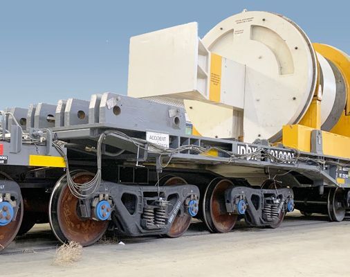 Industrial heavy-haul trailer carrying a large white and yellow cylindrical machine outdoors