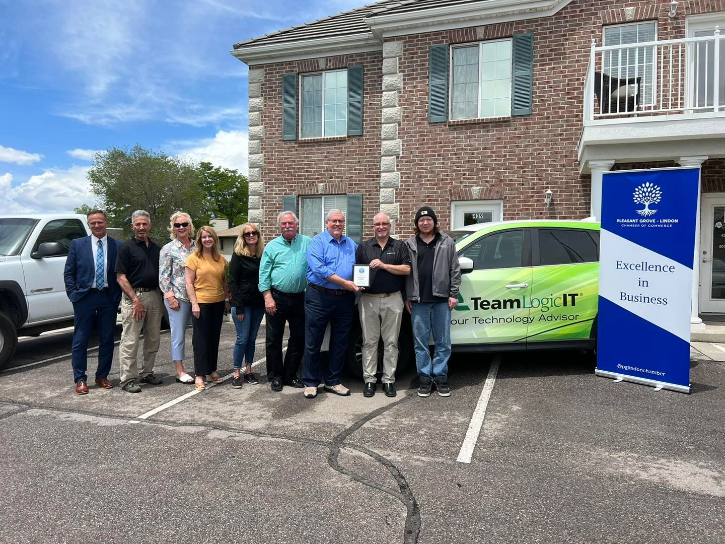 A group of people are standing in front of a green car.