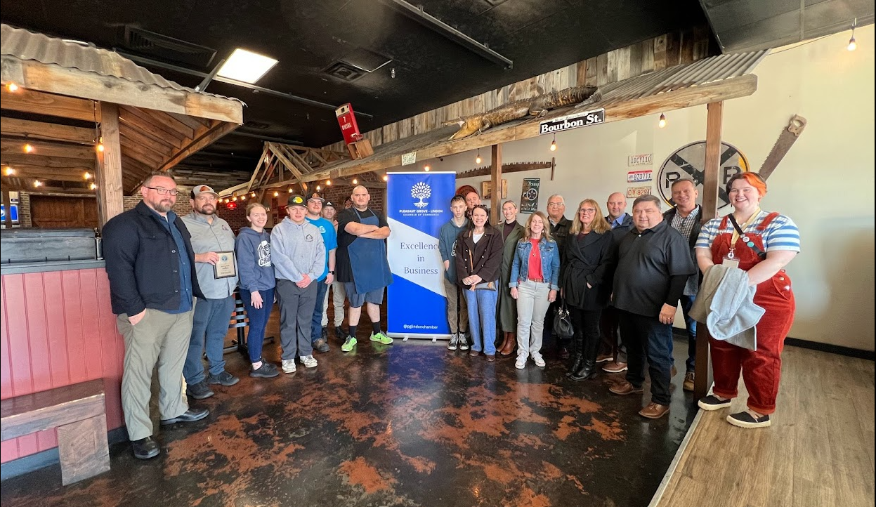 A group of people are standing in a room in front of a sign.