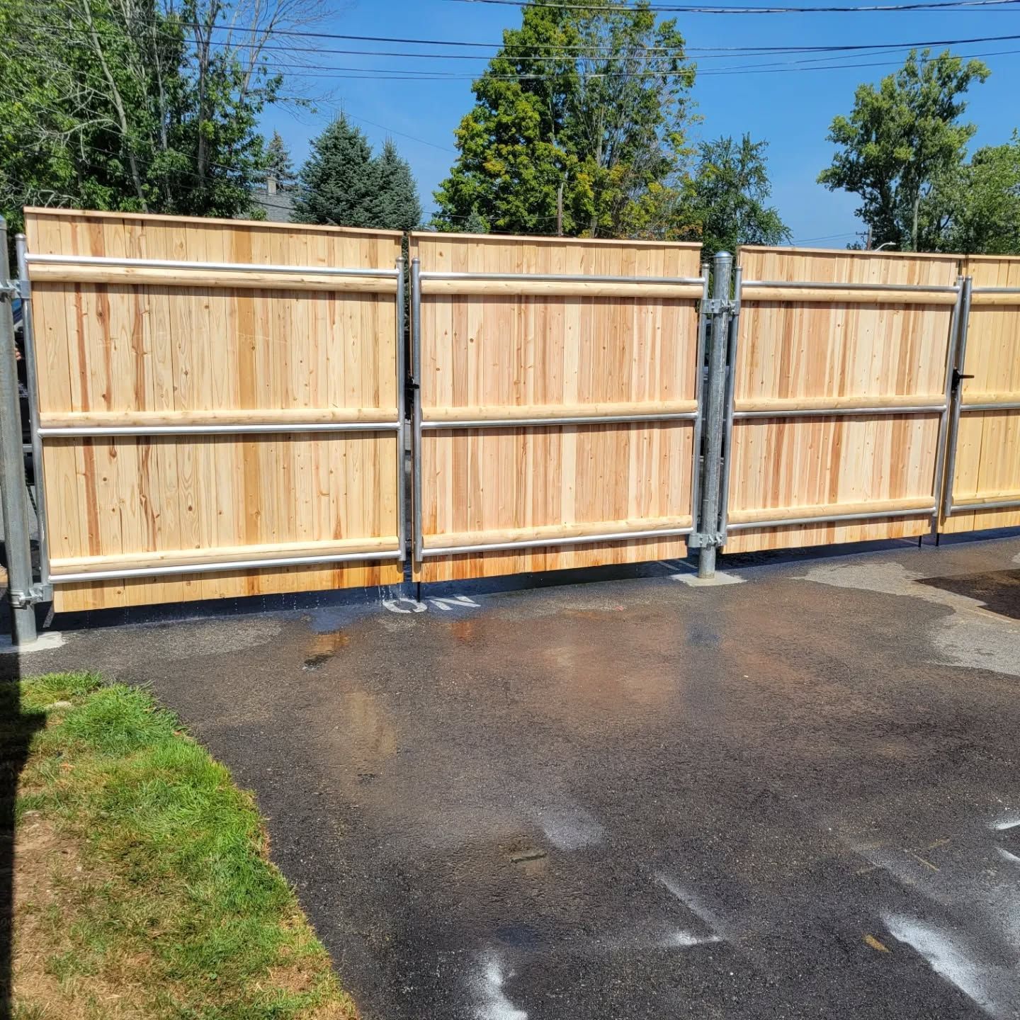 Wooden fence with metal posts on asphalt driveway.