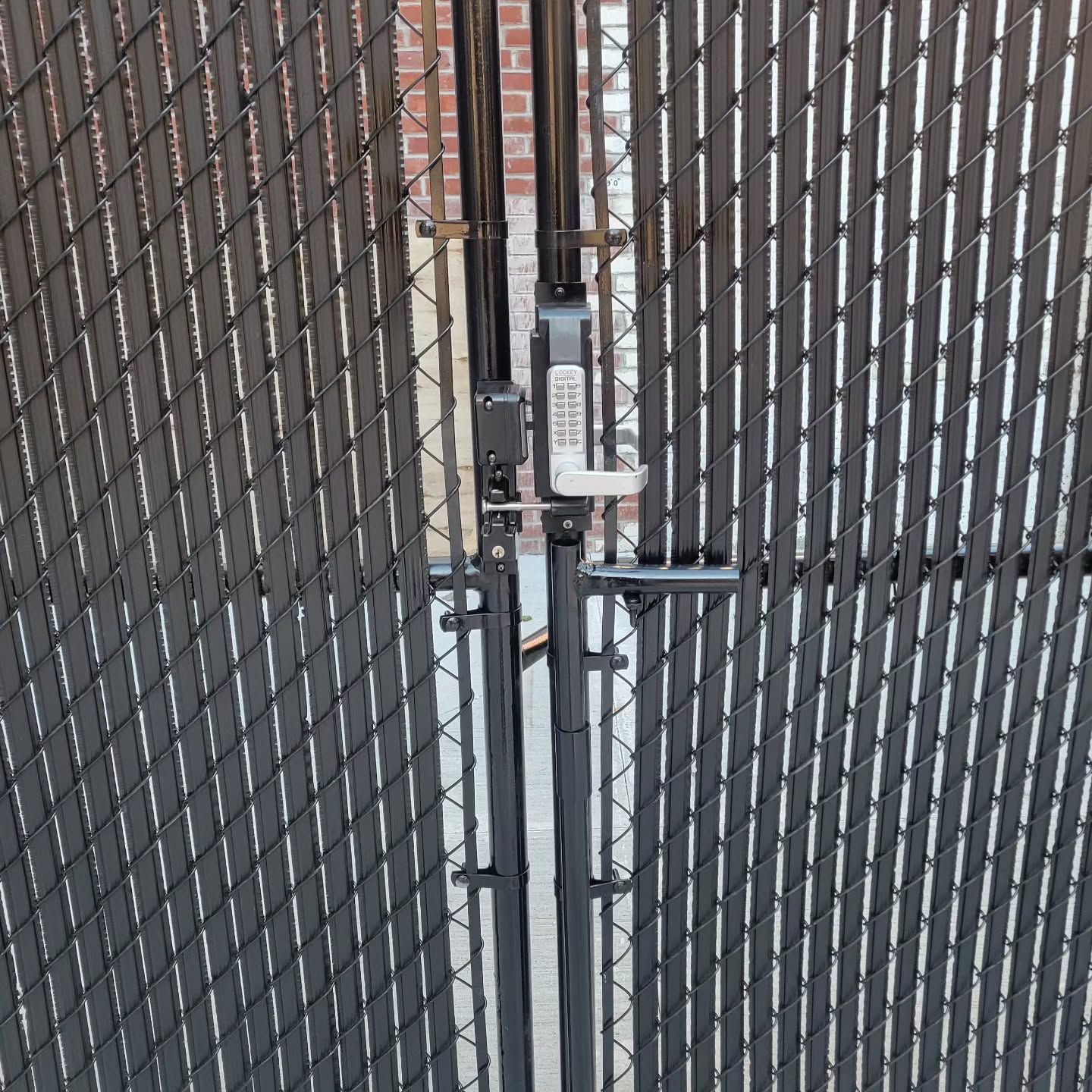 Black chain-link gate with privacy slats, secured by a combination lock and latch.