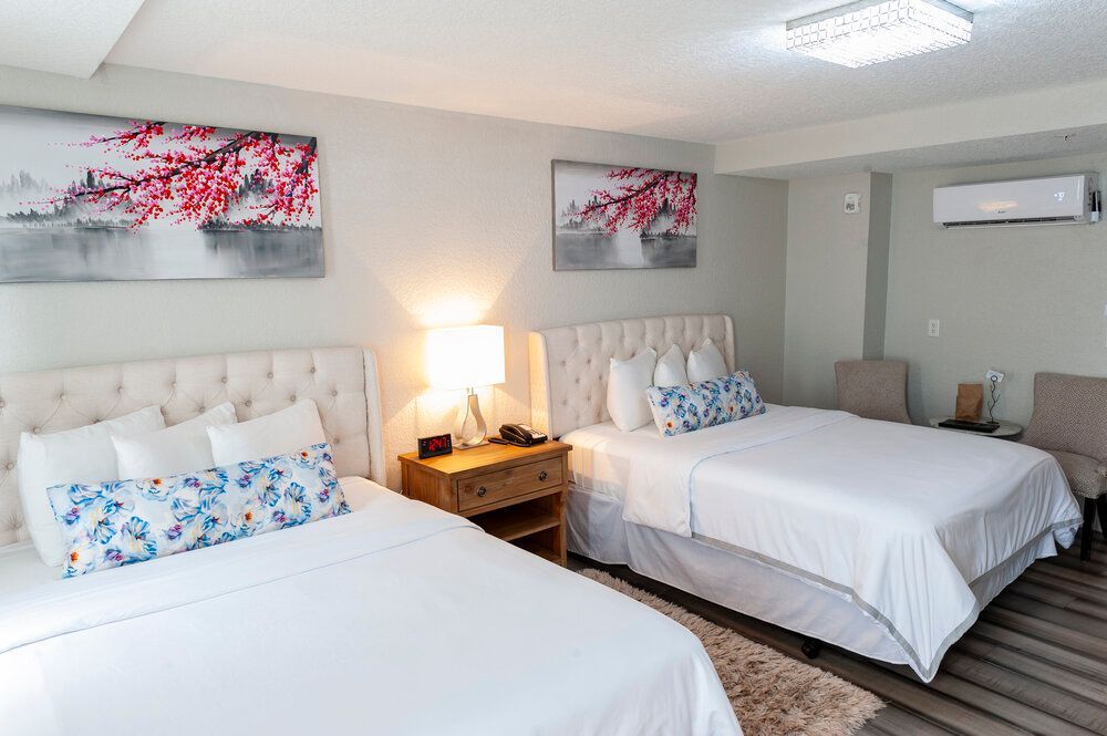 A hotel room with two beds and two chairs.