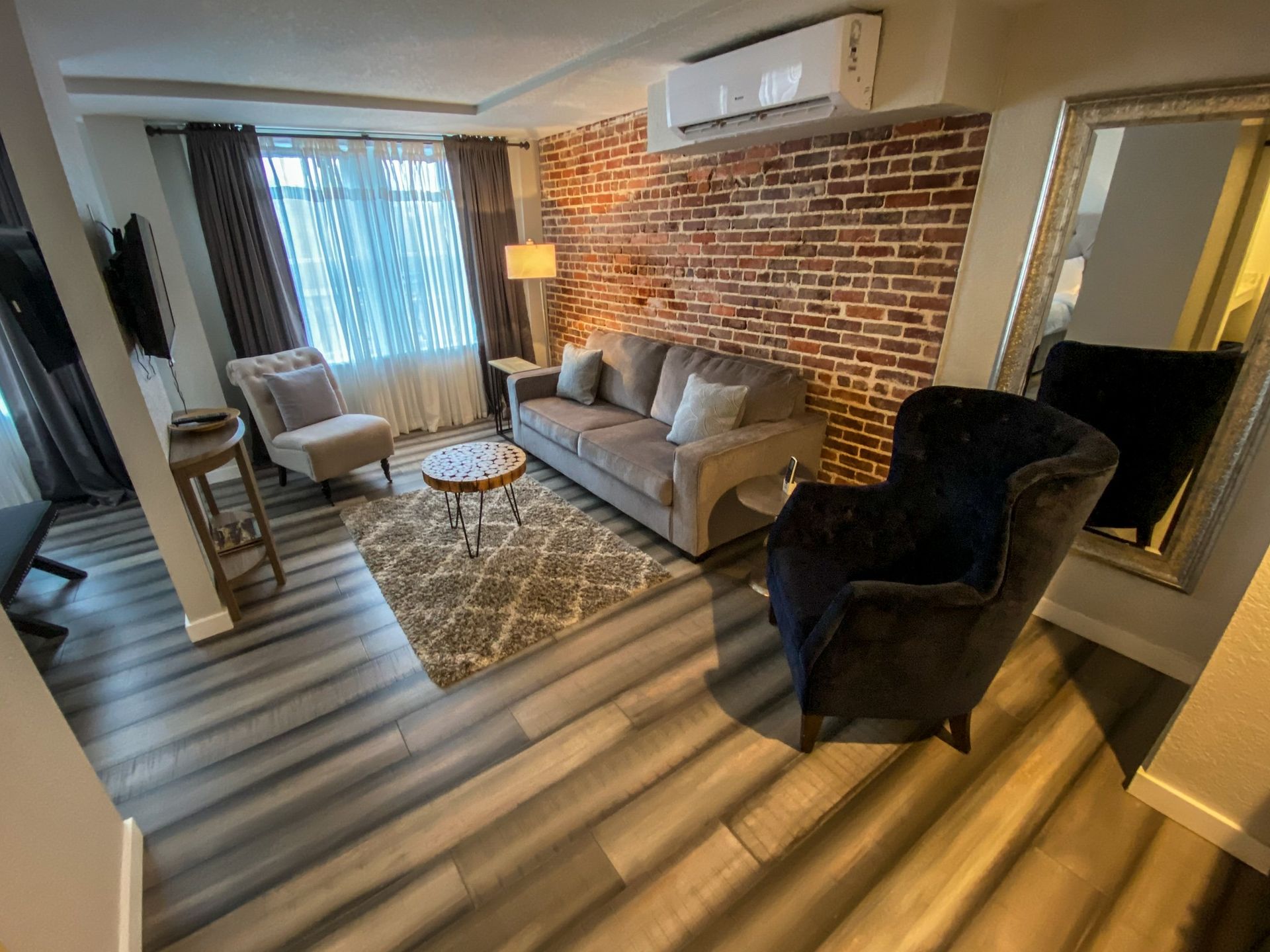 A living room with a couch , chairs , and a mirror.