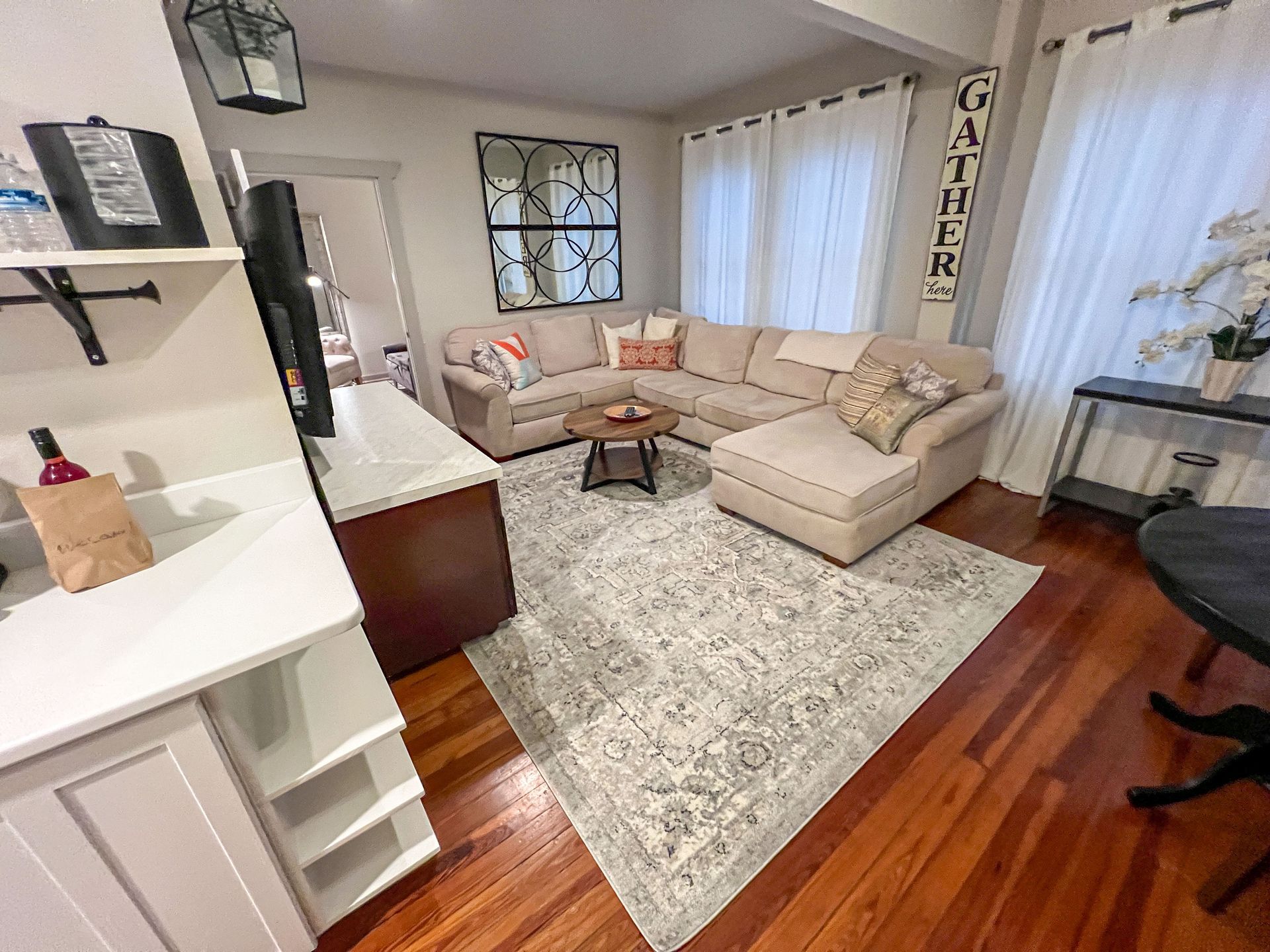 A living room with a sectional couch and a rug.