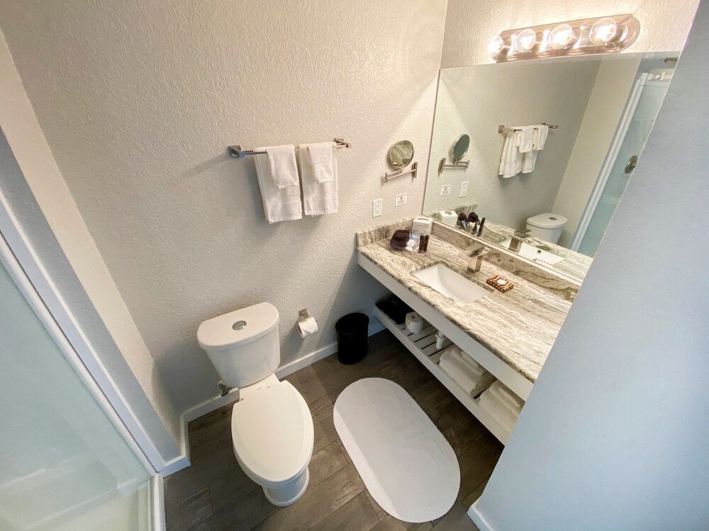 A bathroom with a toilet , sink and mirror.