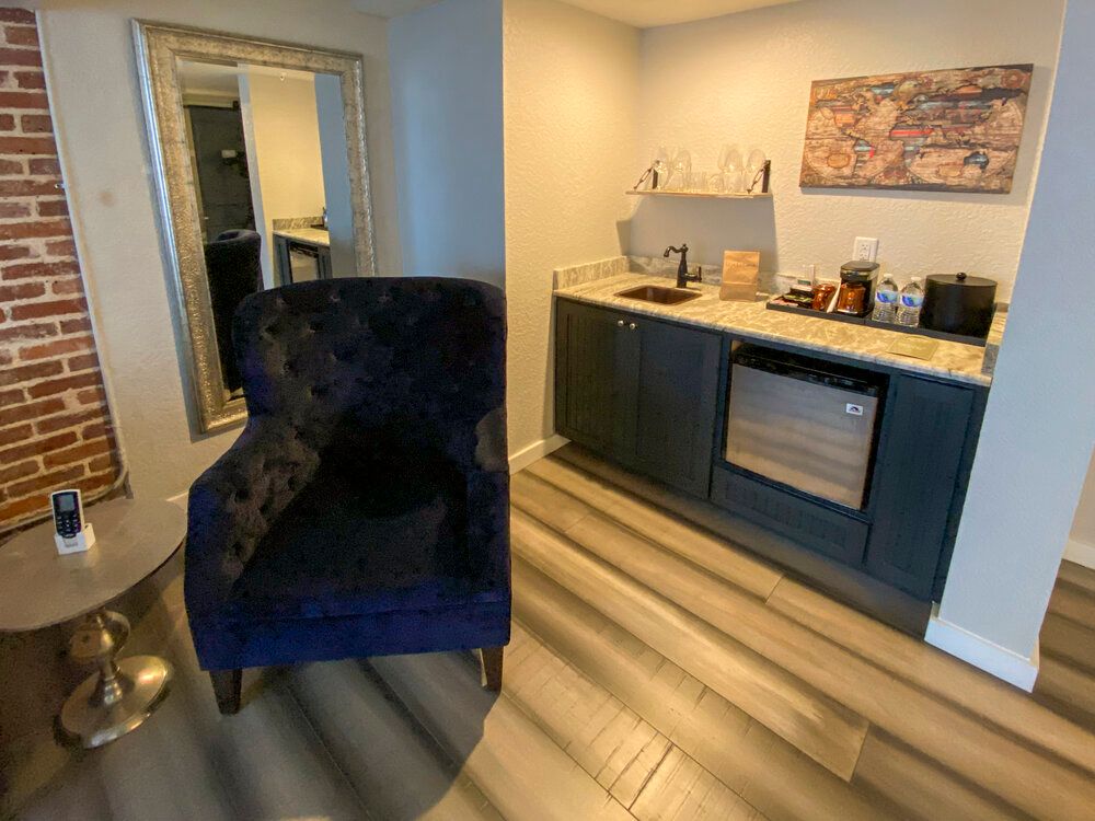 Cozy lounge with navy chair, small table, and coffee bar against the wall.