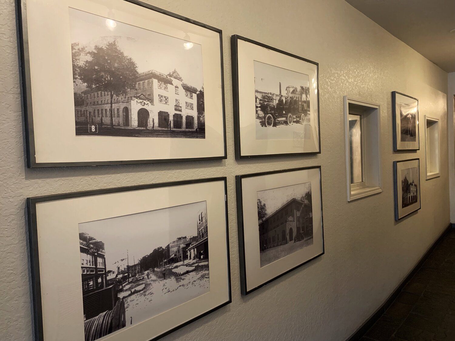 Hallway wall with framed black-and-white photos and a small recessed window or display niche