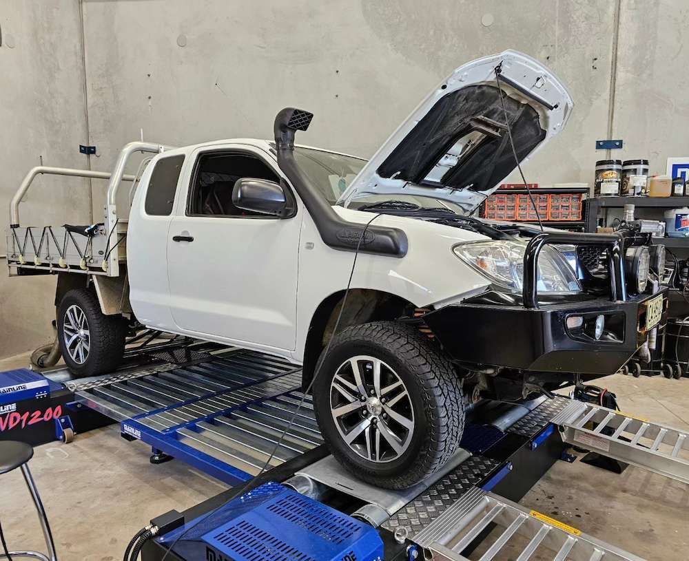 White Pickup Truck on a Dynamometer With the Hood Open in a Garage — Greens Diesel Tune in Camden, NSW