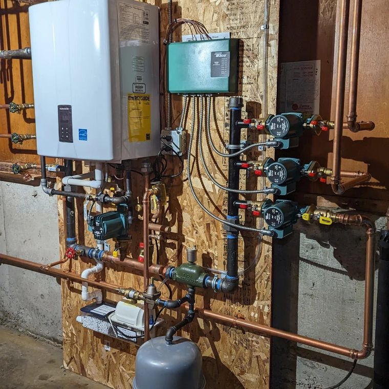A room with a lot of pipes and a boiler on the wall