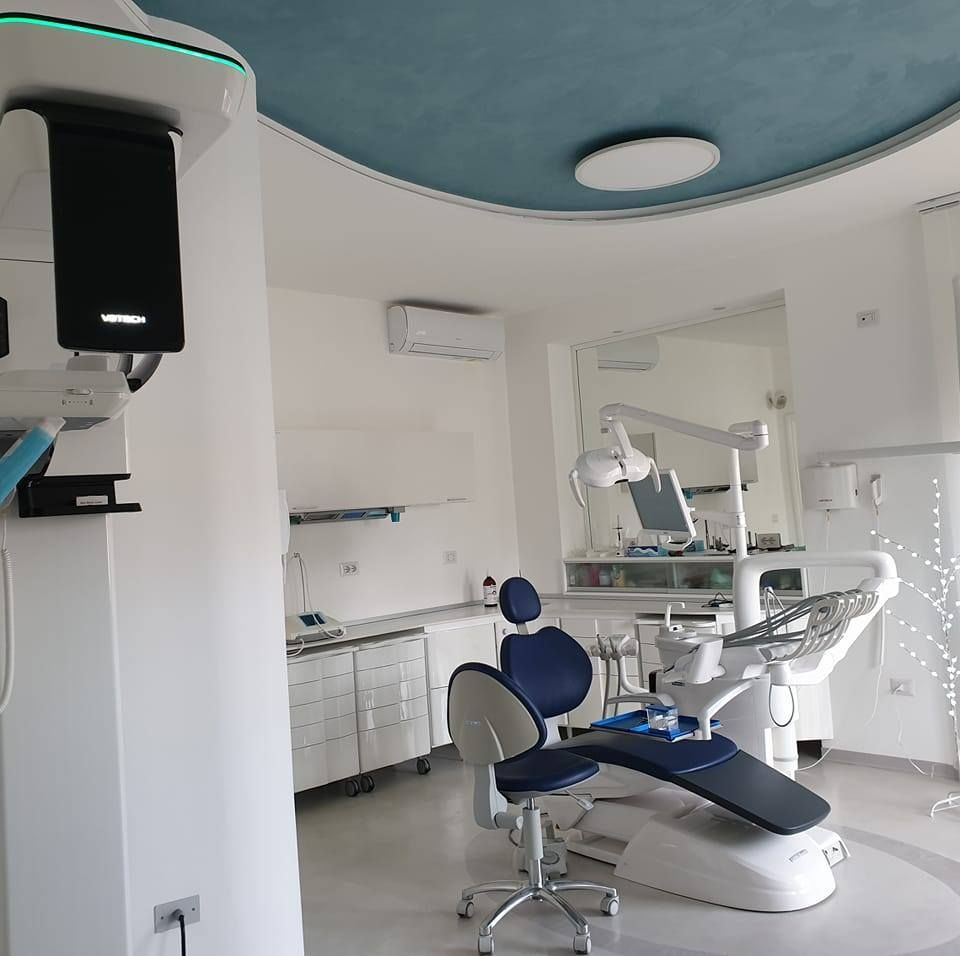 Clinica odontoiatrica moderna con poltrona da dentista blu e bianca, lavandino, armadietti e attrezzatura per le visite.